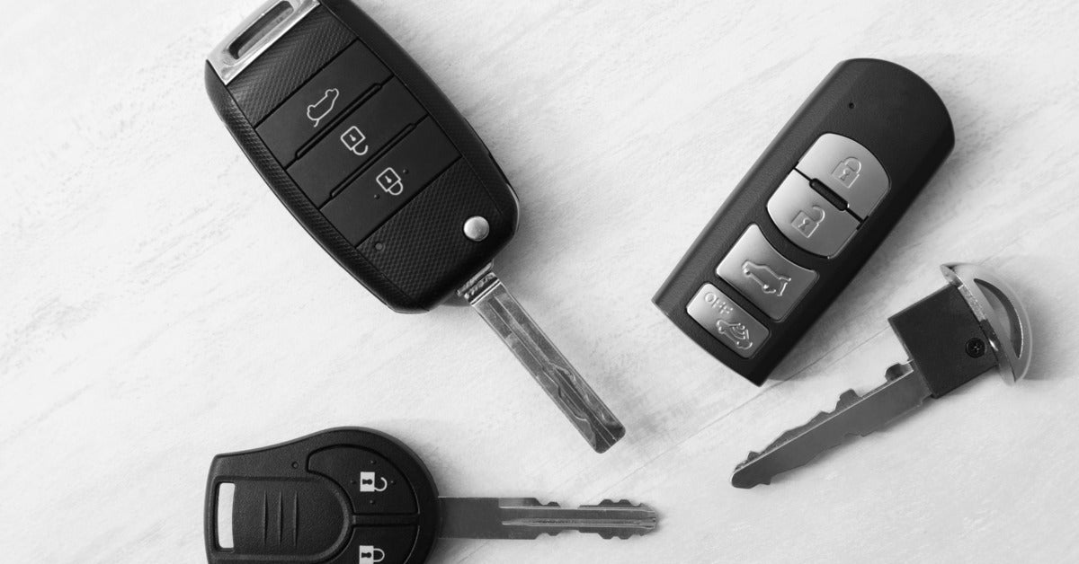 Four different types of modern automotive keys are laying next to each other on a white background.